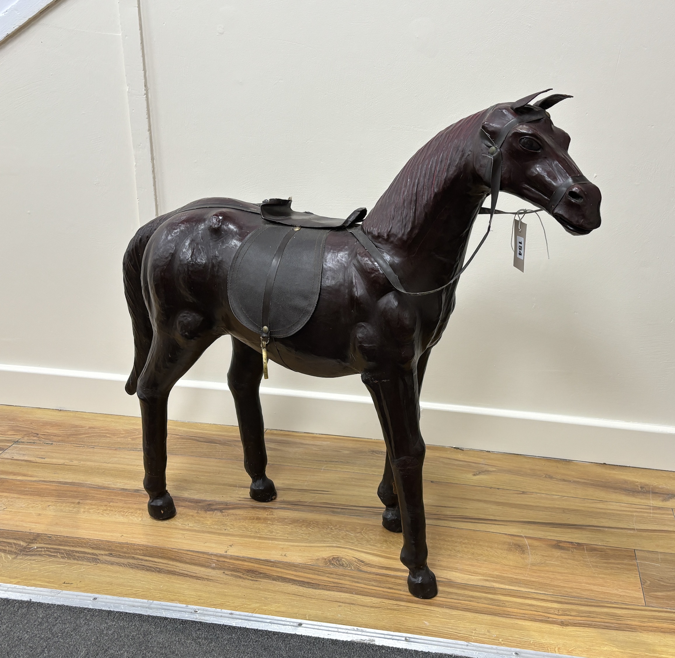 A burgundy leather covered model of a horse with faux leather tack, height 76cm